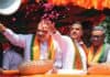 Kolkata Police Register FIRs After Clashes Erupt During Suvendu Adhikari’s Bhowanipore Roadshow With Amit Shah Politician at rally, smiling and waving amid flower petals.