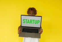 India’s AI Startups Dominate $10.1 Billion FY26 Funding Despite Overall Decline Startup laptop held by person against yellow background.